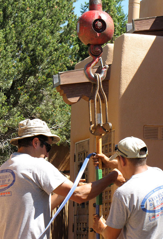 A group of men are strapping something out of view to a crane.